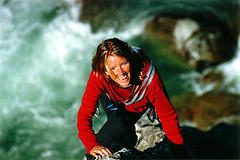 woman climbing up a rock face showing grit on climbing up