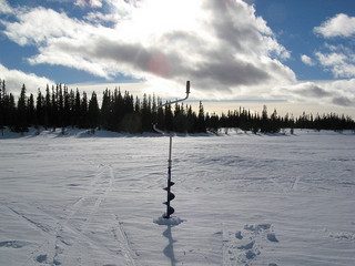 exploring - photo of ice auger drilling hole for ice fishing